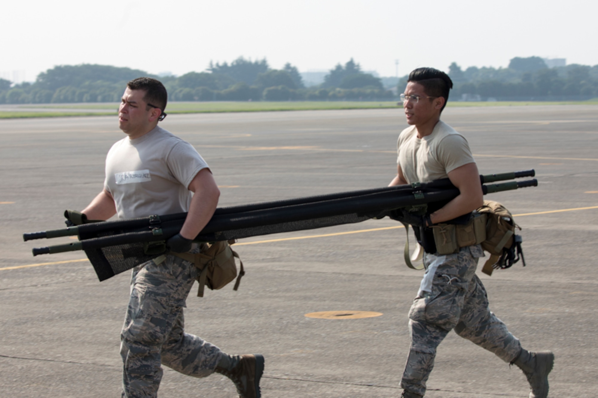 Senior Airman Jonathan Rodriguez and SrA Richson Bacay, both 374th Medical Operations Squadron aerospace medical technicians, carry a stretcher during a major accident response exercise at Yokota Air Base, Japan, July 10, 2017. The training exercise simulated a C-130 Hercules accident with varying levels of injuries. Personnel conducted the drill to ensure they are ready for any aircraft emergency. (U.S. Air Force photo by Yasuo Osakabe)