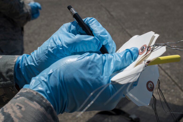 Staff Sgt. Kenny Bradley, 374th Force Support Squadron search and recovery team member, marks an informational tag during a major accident response exercise, June 10, 2017, at Yokota Air Base, Japan. The tags were used to identify simulated body parts during the exercise. (U.S. Air Force photo by Airman 1st Class Juan Torres)