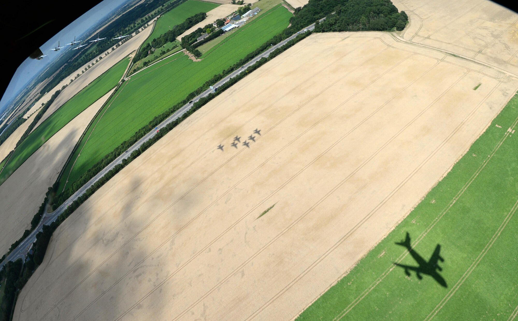 The shadow of six U.S. Air Force Thunderbirds following a U.S. Air Force KC-135 Stratotanker, assigned to the 351st Air Refueling Squadron, is cast over fields, July 10, 2017 near RAF Mildenhall and RAF Lakenheath, England. After performing flyovers above both bases, the formation headed to northern Scotland. (U.S. Air Force photo by Senior Airman Justine Rho)