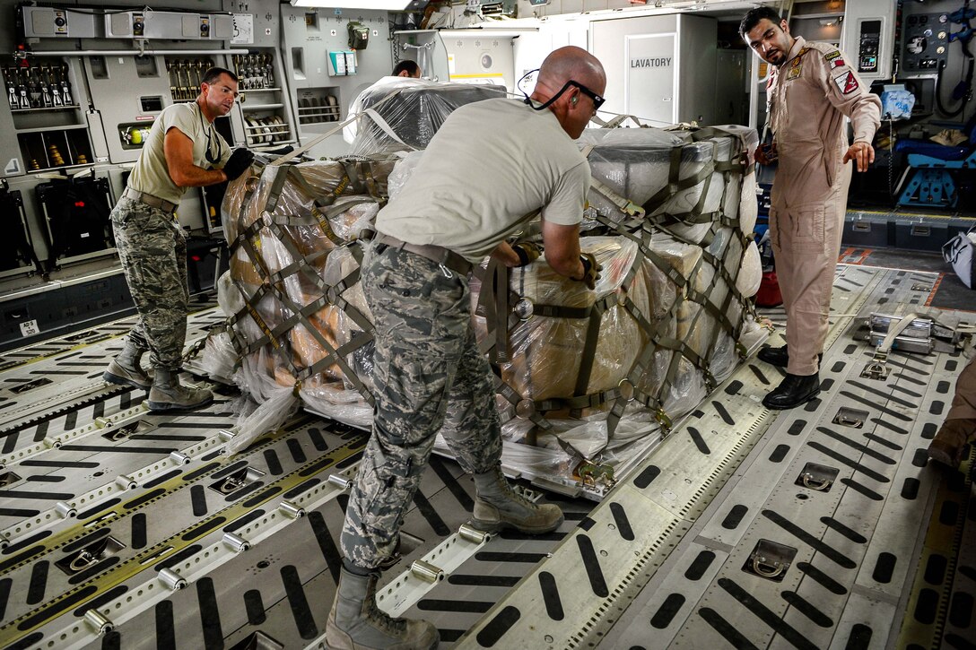 A Qatari airman directs U.S. airmen as they move a pallet of equipment and supplies in a Qatari air force C-17 Globemaster III at Al Udeid Air Base, Qatar, July 2, 2017, for a mission supporting Operation Inherent Resolve. Air Force photo by Staff Sgt. Michael Battles