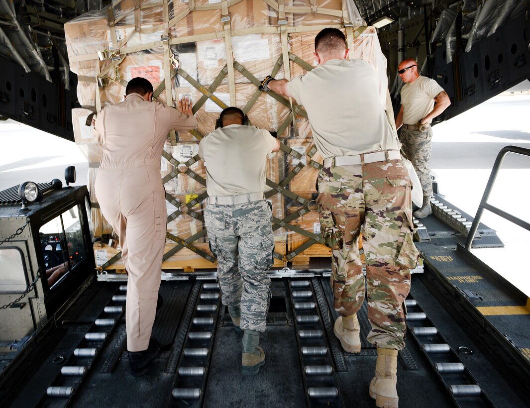 U.S. and Qatari airmen push a pallet of equipment and supplies into a Qatari air force C-17 Globemaster III at Al Udeid Air Base, Qatar, July 2, 2017, before a mission supporting Operation Inherent Resolve. Air Force photo by Staff Sgt. Michael Battles