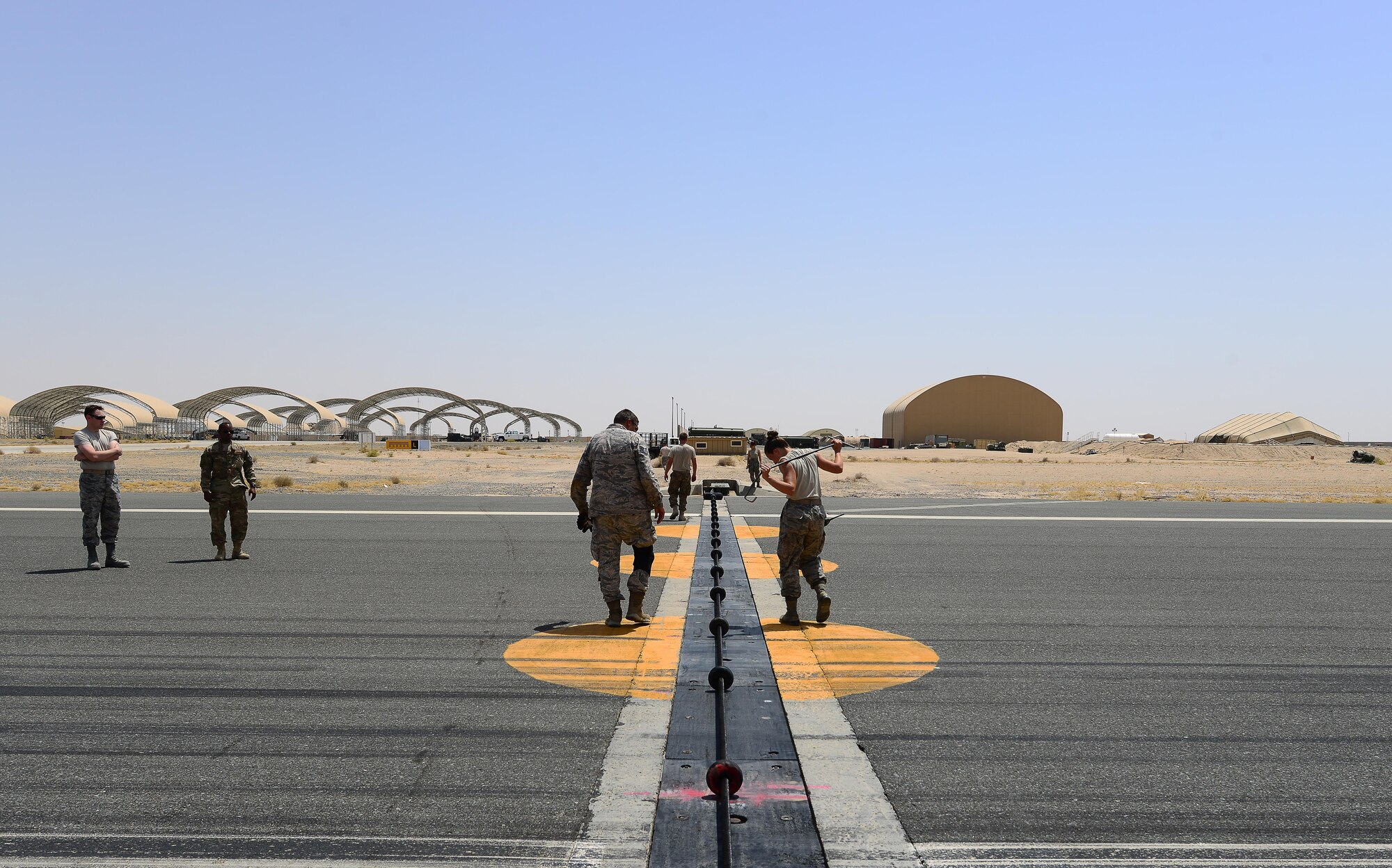 U.S. Air Force power production technicians assigned to the 407th Expeditionary Civil Engineer Squadron, secure the Aircraft Arresting System cable to the Barrier Arresting Kit (BAK-12) in Southwest Asia on July 3, 2017. 407th ECES conducted an Aircraft Arresting System engagement with an Italian AMX A-11 Ghibli aircraft during a simulated in-flight emergency. (U.S. Air Force photo by Tech. Sgt. Andy M. Kin)