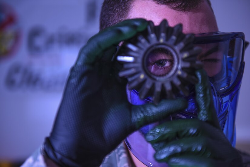 Senior Airman Brett Gyurnek, 437th Maintenance Squadron Non-Destructive Inspection technician, looks through a core reverser gear while performing a fluorescent penetrant test at Joint Base Charleston, S.C. July10, 2017. The NDI shop is able to test the largest and smallest pieces of an aircraft. Once a deficiency is found, it is relayed to the aircraft structural maintenance unit for repair. If a crew chief or a member of the aircrew identifies a potential issue, NDI Airmen perform diagnostic procedures to determine the extent of the damage. 