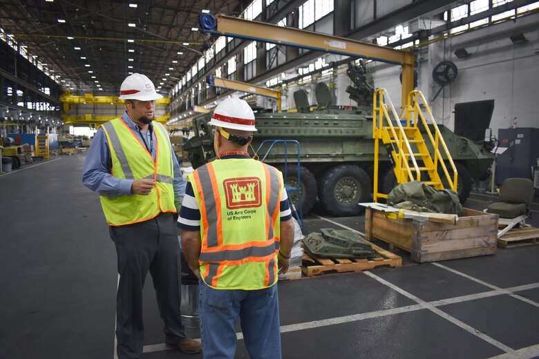 Chad McLeod, area engineer, South Alabama Area Office, Mobile District; at left, speaks to John McLain, resident engineer; in the 41,000 square feet of the facility where metal cleaning, finishing and painting takes place for many Army vehicles. Mobile District recently completed a $9.5 million modernization of the building.