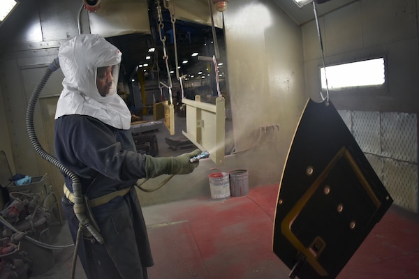 A technician uses the new paint booth area which was built during building 409’s $9.5 million modernization. The administration area and break room were renovated; and a new break room and safety suit storage area were created.