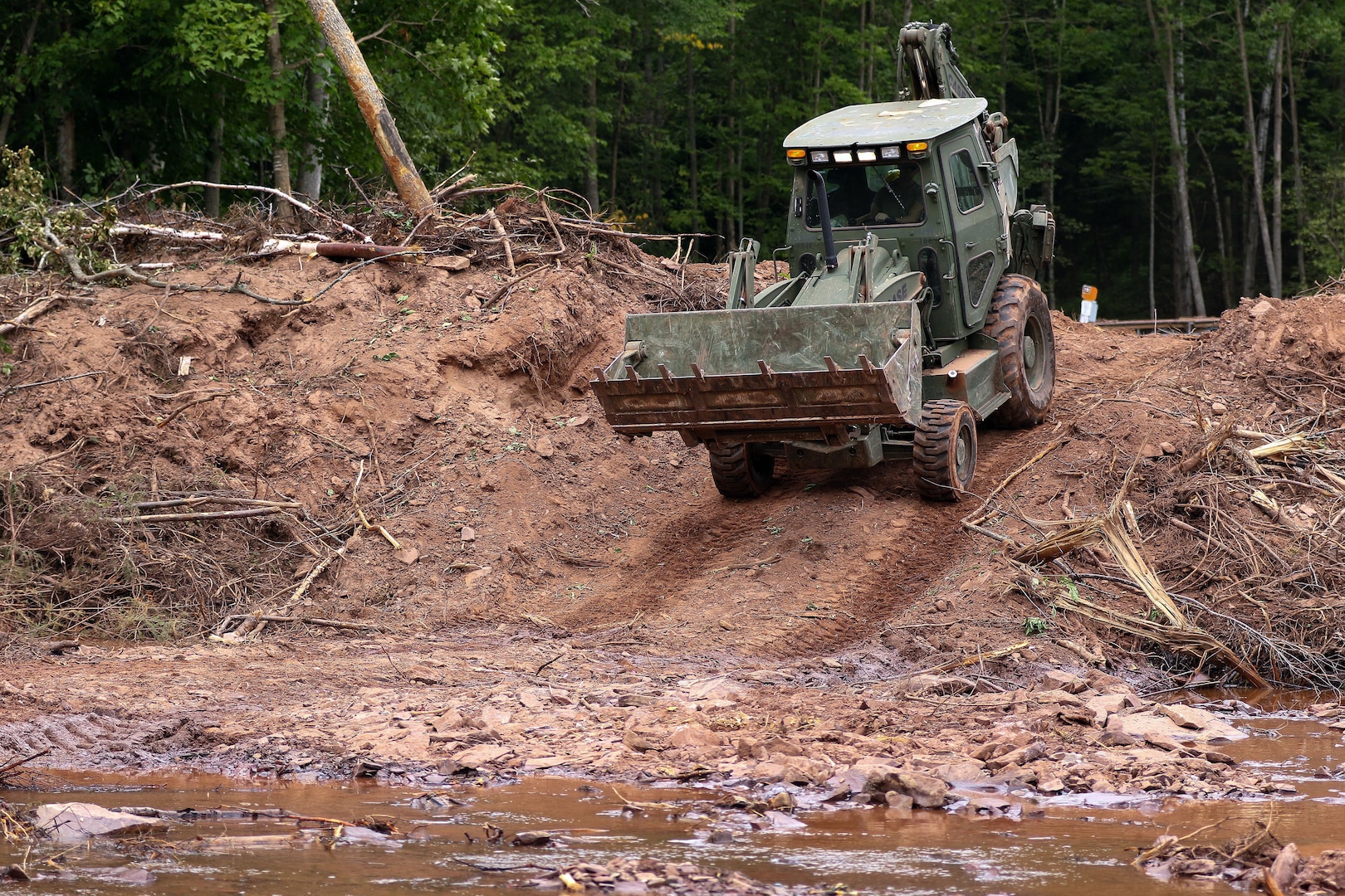 Wisconsin National Guard troops are mobilized to assist three flood-stricken communities. In this photo from Aug. 9, 2016, a Guard front loader clears debris from the Oronto Creek in Iron County, Wis.