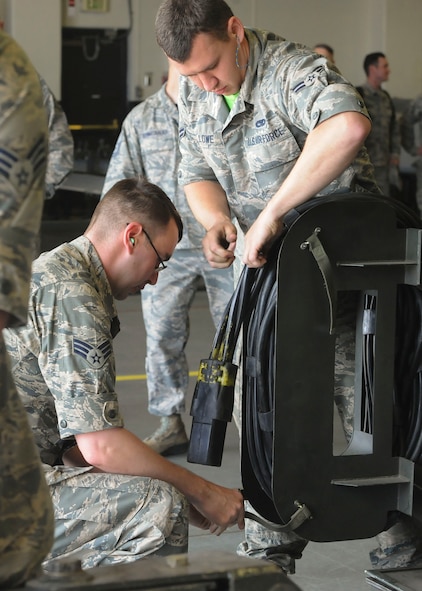 (From left) Senior Airman Joshua Laskowski and Airman 1st Class Jacob Lowe, 705th Munitions Squadron maintenance team members, secure power cables to a rotary launcher at Minot Air Force Base, N.D., June 30, 2017. The power cables control brake lights and provide hydraulic fluid to the common strategic rotary launcher trailer. (U.S. Air Force photo by Airman 1st Class Jessica Weissman)