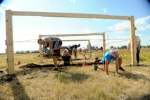Airmen and their families make their way through an obstacle during the 2017 Mud Like You Mean It race at Minot Air Force Base, N.D., July 7, 2017. The event consisted of various obstacles that challenged their ability to crawl, climb, run and slide through mud and water. (U.S. Air Force photo by Senior Airman Sahara L. Fales)
