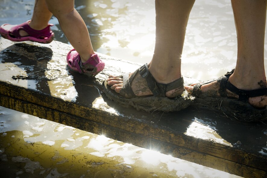 A child and their parent walk across a plank during the 2017 Mud Like You Mean It race at Minot Air Force Base, N.D., July 7, 2017. The event consisted of various obstacles that challenged their ability to crawl, climb, run and slide through mud and water. (U.S. Air Force photo by Senior Airman Sahara L. Fales)