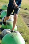A child runs across exercise balls during the 2017 Mud Like You Mean It race at Minot Air Force Base, N.D., July 7, 2017. Approximately 600 Airmen and their families attended the event, which lasted two hours. (U.S. Air Force photo by Senior Airman Sahara L. Fales)