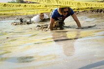 Col. William Barrington, 91st Maintenance Group commander, and Col. Catherine Barrington, 91st Operations Group commander, crawl through mud at Minot Air Force Base, N.D., July 7, 2017. The low-crawl was one of many obstacles that tested participants’ balance, endurance and strength. (U.S. Air Force photo by Senior Airman Sahara L. Fales)