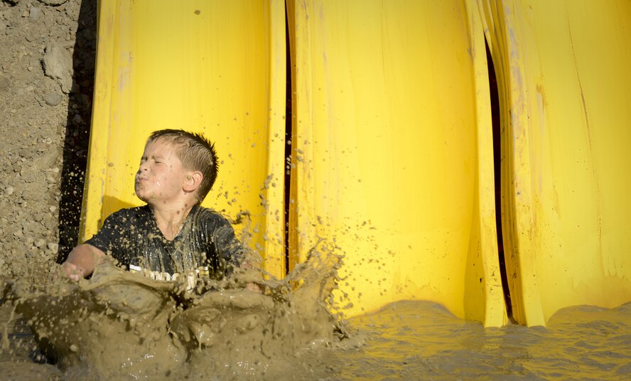 A child falls into a mud pool during the 2017 Mud Like You Mean It race at Minot Air Force Base, N.D., July 7, 2017. The event had various obstacles that tested participants’ balance, endurance and strength. (U.S. Air Force photo by Senior Airman Sahara L. Fales)