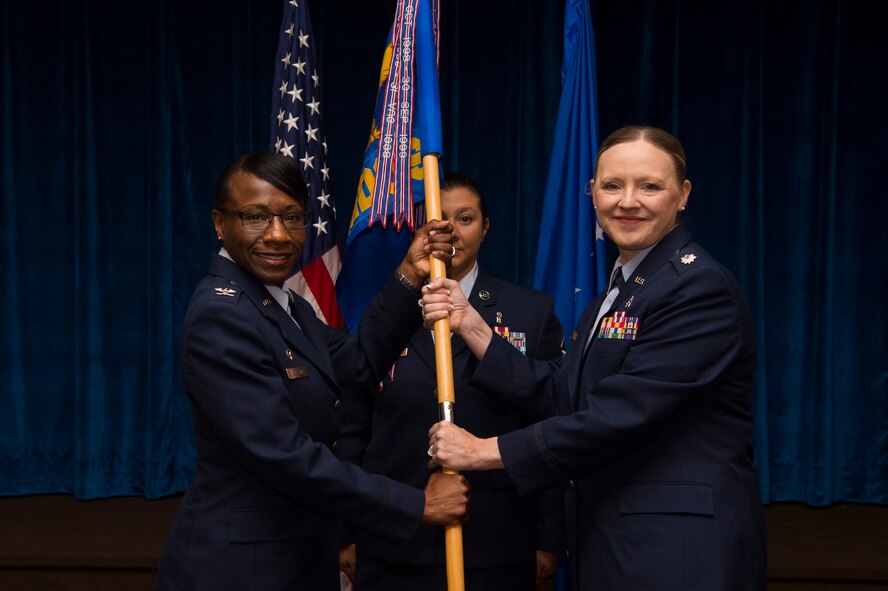 Col. Cherron Galluzzo, 90th Medical Group commander, passes the guidon to Lt. Col. Angela Lacek, 90th Medical Operations Squadron commander, during the 90th MDOS change of command ceremony at F.E. Warren Air Force Base, Wyo., July 13, 2017. The ceremony signified the transition of command from Lt. Col. John Modra. (U.S. Air Force photo by Staff Sgt. Christopher Ruano)