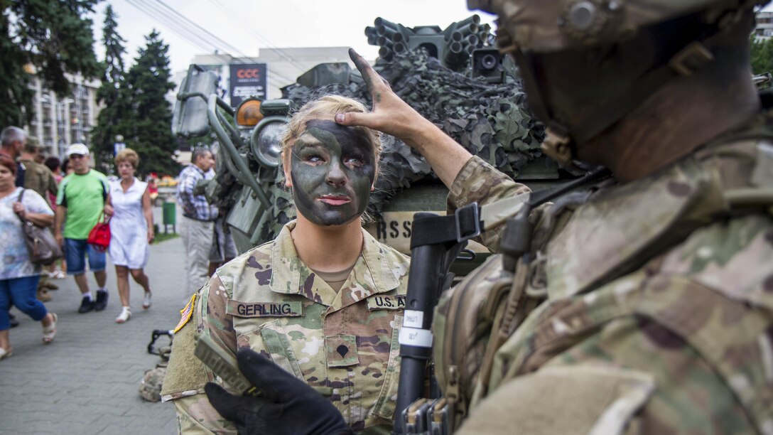 A soldier applies camouflage paint to another soldier as their unit hosts a static display of stryker vehicles during Dragoon Guardian, an exercise in Ploiești, Romania, July 12, 2017. Army photo by Capt. Jeku Arce

