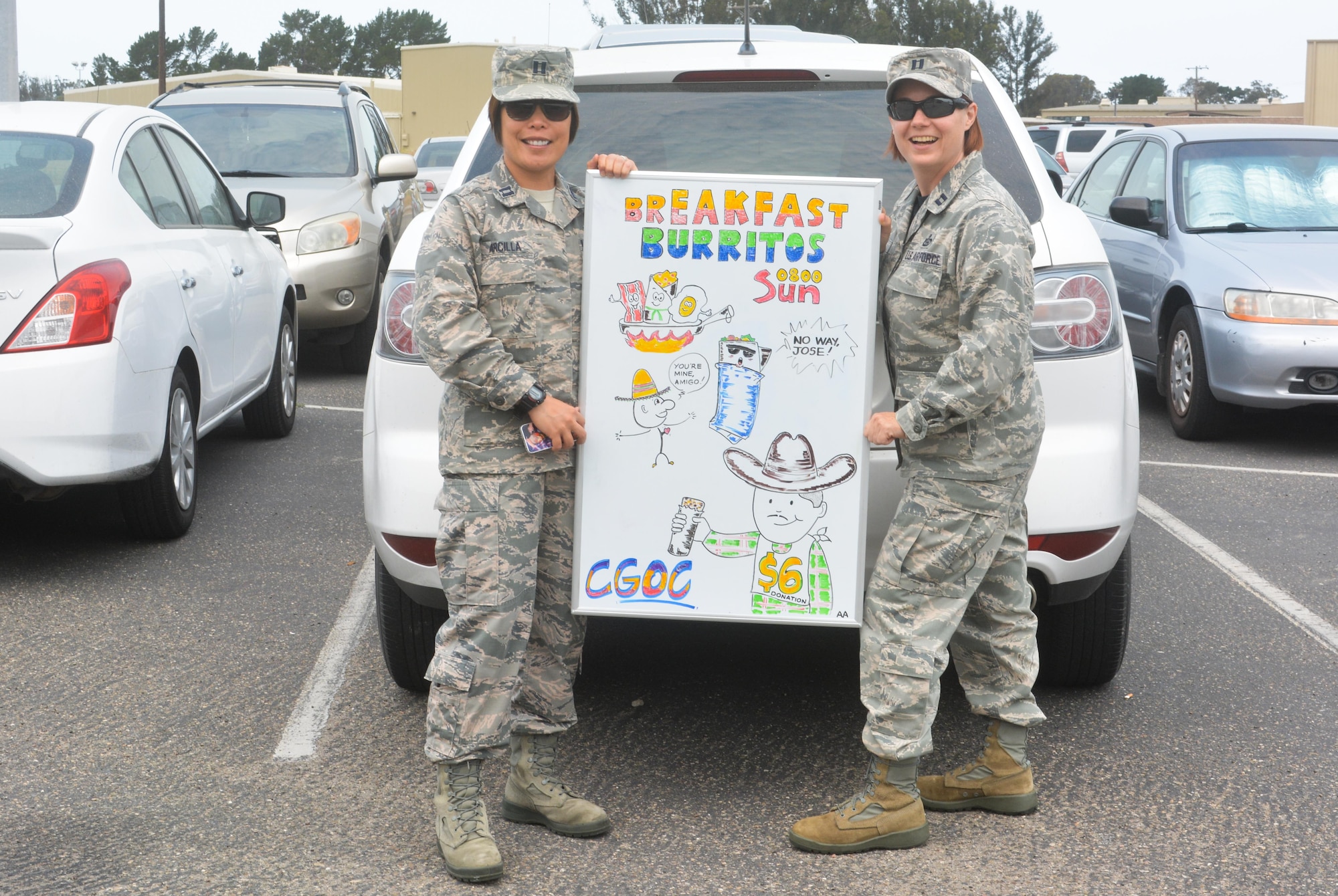 VANDENBERG AIR FORCE BASE, Cali. -- Members of the 9th Combat Operations Squadron, Capt. Aprille Arcilla and Capt. Laura Peyton, pose with a sign Arcilla created in support of their Company Grade Officers' Council on Sunday, July 9, 2017. Breakfast burritos were offered to Col. Traci Kueker-Murphy, 310th Space Wing commander, and Command Chief Master Sgt. Todd Scott while they were there visiting the unit. (U.S. Air Force photo/Senior Airman Laura Turner)