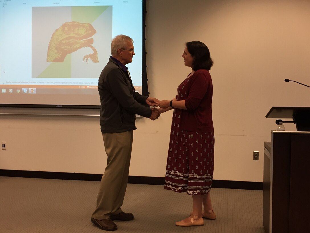Retired Air Force Lieutenant General Christopher A. Kelly, Director of the Center for Joint & Strategic Logistics, presents a coin to Ms. Rebecca Jensen of The Case Method Project for her outstanding presentation on the use of case studies to enhance student learning during the 2017 Joint Logistics Faculty Development Workshop.