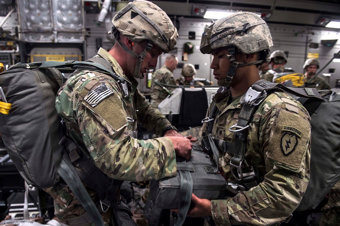 Army Spc. Isaiah Madalora, right, assists Army Sgt. Zachary Hudson with a parachute aboard a C-17 Globemaster III, July 12, 2017, before participating in Exercise Talisman Saber 2017. Madalora and Hudson are assigned to the 25th Infantry Division’s 4th Brigade. Air Force photo by Tech. Sgt. Gregory Brook 