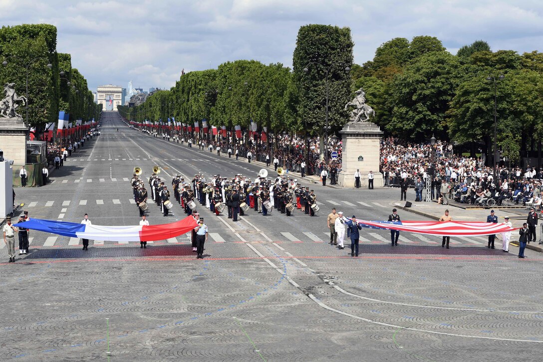 U.S. and French service members display their nations' respective flags during the Bastille Day military parade in Paris, July 14, 2017. Navy photo by Chief Petty Officer Michael McNabb