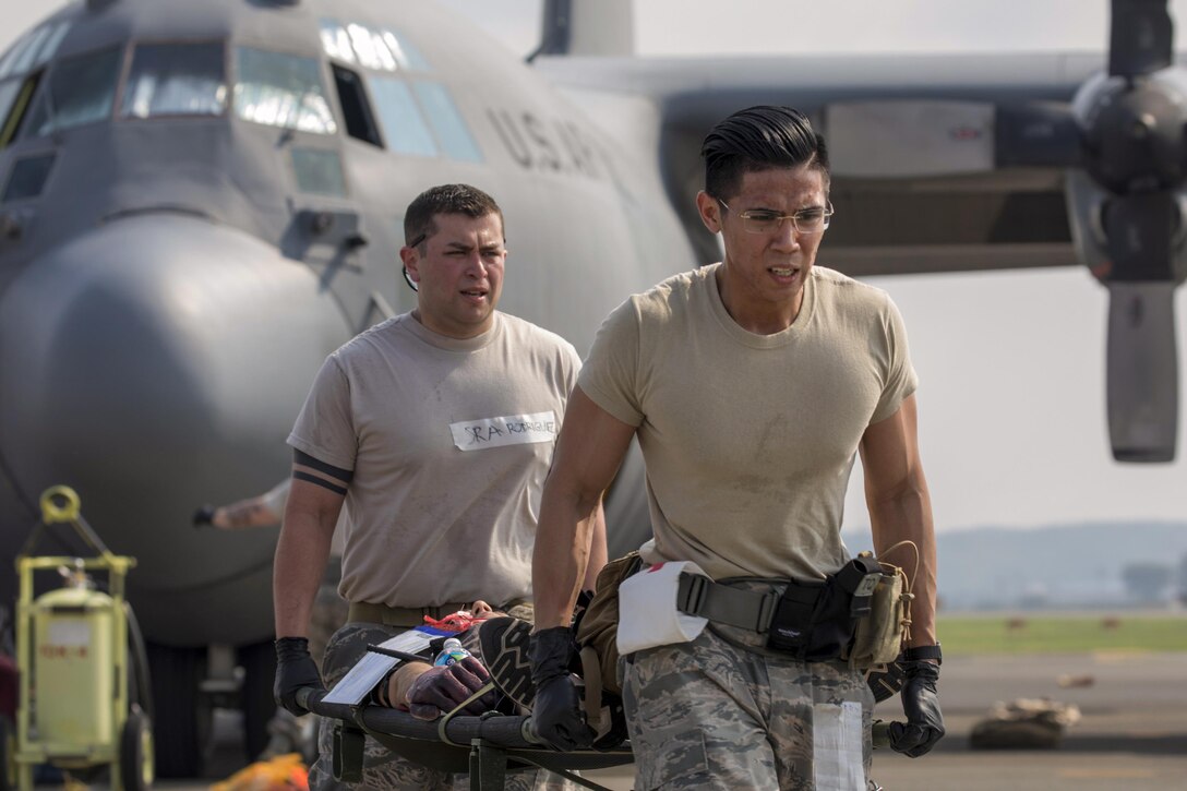 Air Force Senior Airman Richson Bacay and Senior Airman Jonathan Rodriguez carry a simulated aircraft accident victim to safety during a major accident response exercise at Yokota Air Base, Japan, July 10, 2017. The exercise is an annual training requirement for the base to test its readiness and response capabilities. Air Force photo by Yasuo Osakabe