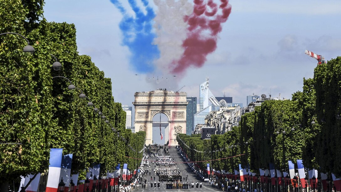 U.S. service members march in the Bastille Day parade in Paris, July 14, 2017, as smoke trails billow overhead from a flyover conducted by French Alpha jets. U.S. troops led the parade in a historic first to commemorate the centennial of America’s entry into World War I, as well as its long-standing partnership with France. Navy photo by Chief Petty Officer Michael McNabb