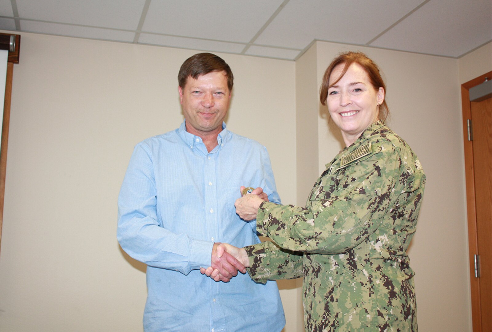 Defense Logistics Agency Land and Maritime Commander Navy Rear Adm. Michelle Skubic presents her commander’s coin for excellence to John Iverson during a July 10 site visit and review at DLA Maritime at Puget Sound Naval Shipyard in Bremerton, Wash. Iversen is a purchasing agent at DLA Maritime at Puget Sound.
