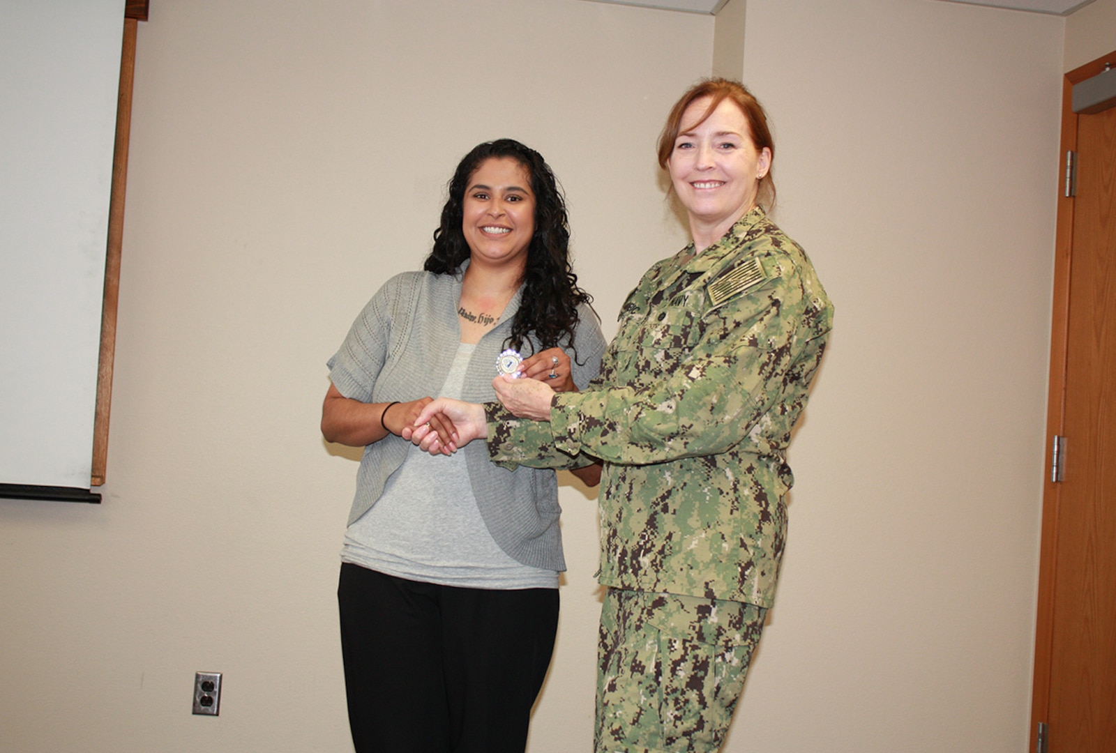 Defense Logistics Agency Land and Maritime Commander Navy Rear Adm. Michelle Skubic presents her commander’s coin for excellence to Gisselle Lopez during a July 10 site visit and review at DLA Maritime at Puget Sound Naval Shipyard in Bremerton, Wash. Lopez is a supply technician at DLA Maritime at Puget Sound.