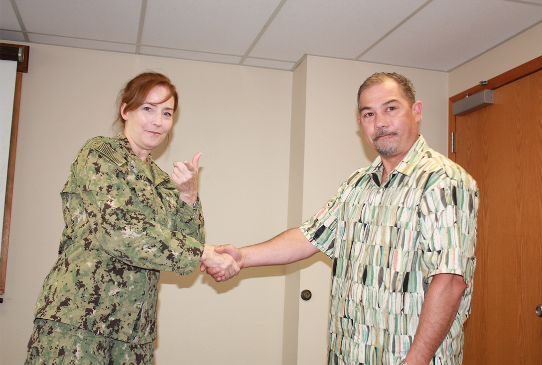 Defense Logistics Agency Land and Maritime Commander Navy Rear Adm. Michelle Skubic presents her commander’s coin for excellence to Robert Reed during a July 10 site visit and review at DLA Maritime at Puget Sound Naval Shipyard in Bremerton, Wash. Reed is a general supply specialist at DLA Maritime at Puget Sound.