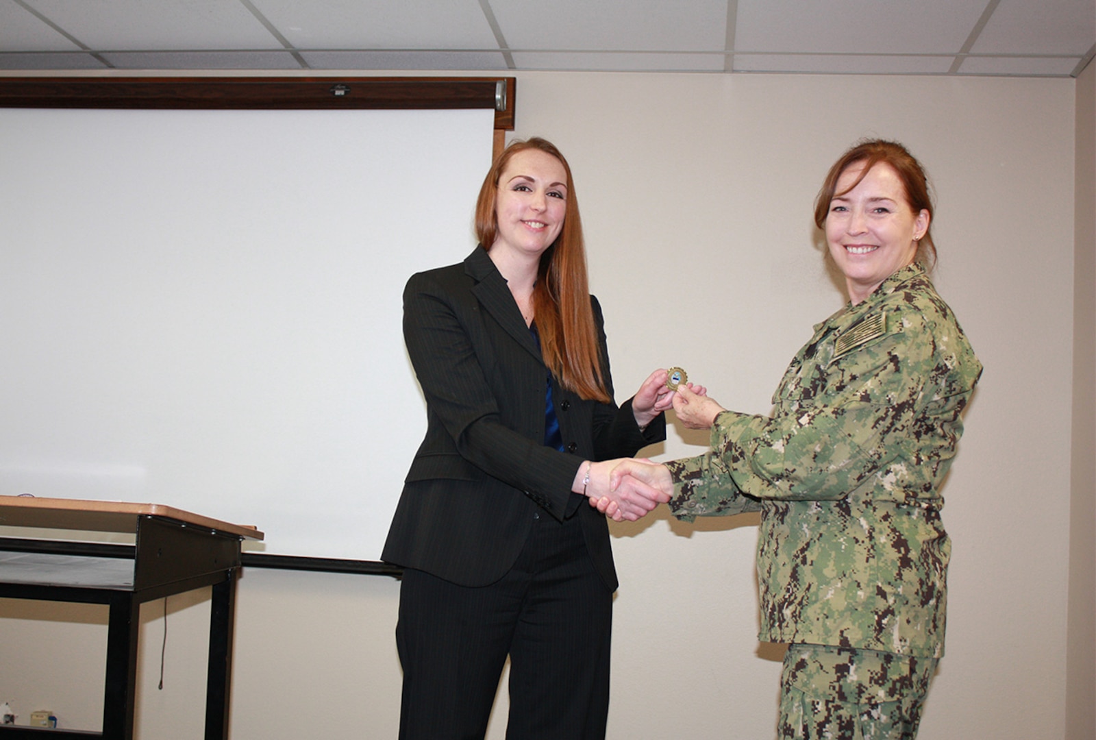 Defense Logistics Agency Land and Maritime Commander Navy Rear Adm. Michelle Skubic presents her commander’s coin for excellence to Ryen Joyce during a July 10 site visit and review at DLA Maritime at Puget Sound Naval Shipyard in Bremerton, Wash. Joyce is a material support division manager at DLA Maritime at Puget Sound.