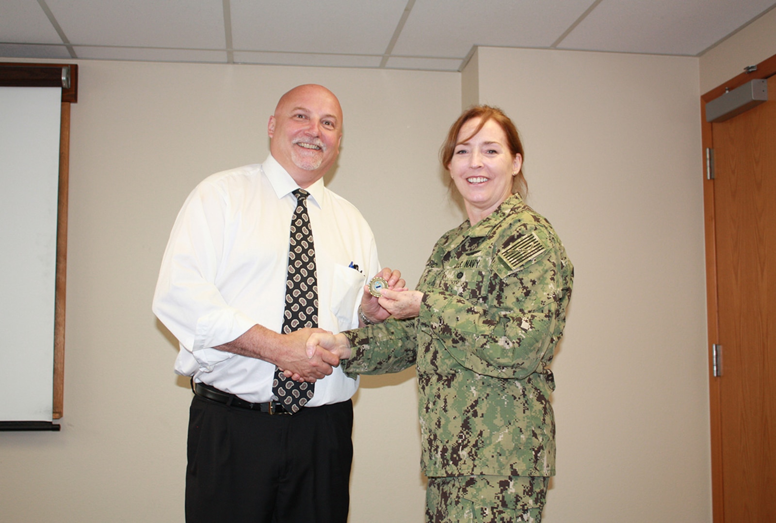 Defense Logistics Agency Land and Maritime Commander Navy Rear Adm. Michelle Skubic presents her commander’s coin for excellence to Brian Mueller during a July 10 site visit and review at DLA Maritime at Puget Sound Naval Shipyard in Bremerton, Wash. Mueller serves as deputy director of DLA Maritime at Puget Sound.