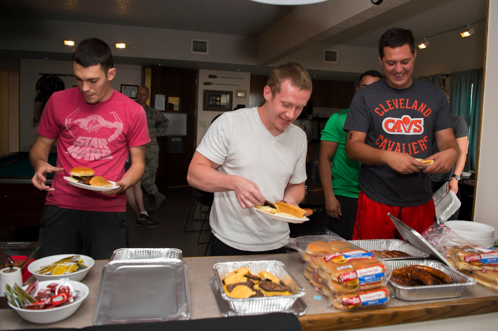Airmen from the 90th Missile Maintenance Squadron gather brats and burgers on their plates during the 319th Missile Squadron code change burger burn in the 90th Missile Wing missile complex, July 12, 2017. Security forces plus maintenance members, chefs and missile crews were given an opportunity to bond over home-cooked meals and make connections across various career fields, furthering the camaraderie of the Mighty Ninety family. (U.S. Air Force photo by Staff Sgt. Christopher Ruano)