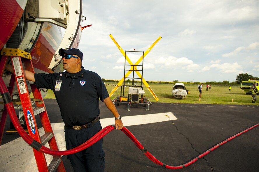 Santos Elizonda, San Angelo firefighter, runs an air hose through an commercial passenger airplane during a plane crash exercise at the Mathis Regional Airport San Angelo, Texas, July 13, 2017. The exercise helped measure how emergency services from San Angelo would respond to a plane crash. (U.S. Air Force photo by Senior Airman Scott Jackson/Released)