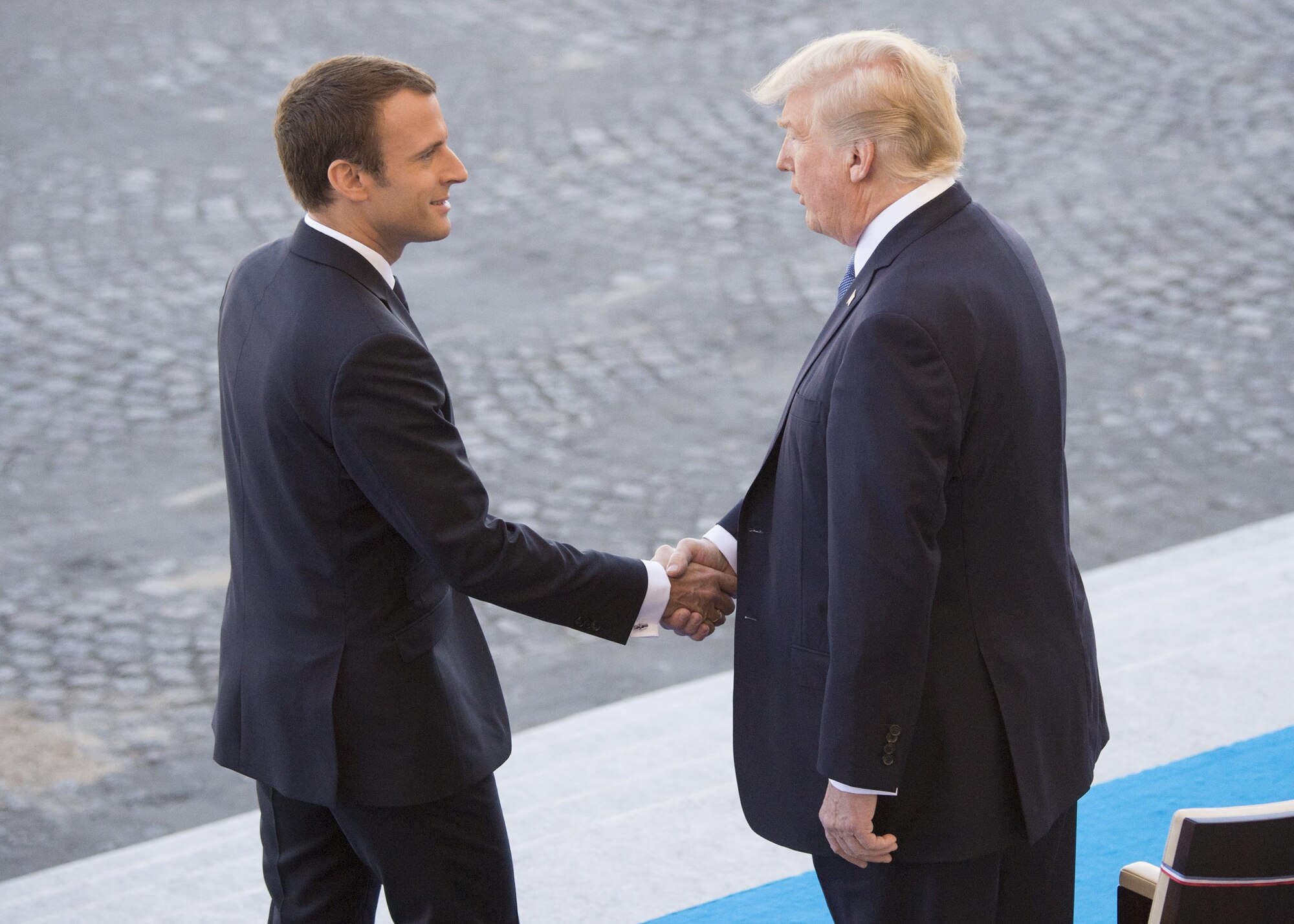 French President Emmanuel Macron welcomes President Donald J. Trump to the reviewing stand for the Bastille Day military parade in Paris, July 14, 2017. Macron and Trump recognized the continuing strength of the U.S.-France alliance from World War I to today.