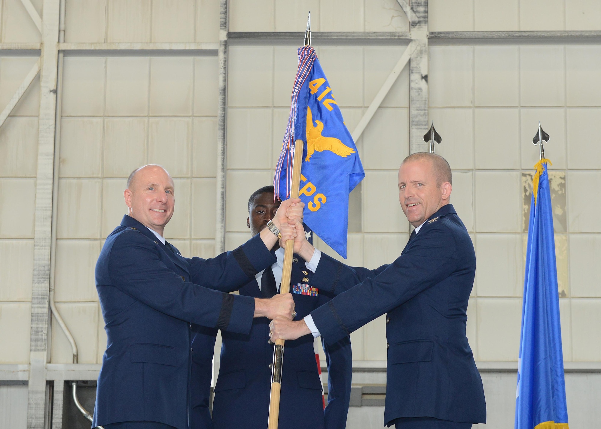 Brig. Gen. Carl Schaefer, 412th Test Wing commander (left), and new U.S. Air Force Test Pilot School commandant, Col. Matthew Higer, pose with the school’s guidon during a change of command ceremony in Hangar 1207 July 14. (U.S. Air Force photo by Kenji Thuloweit)