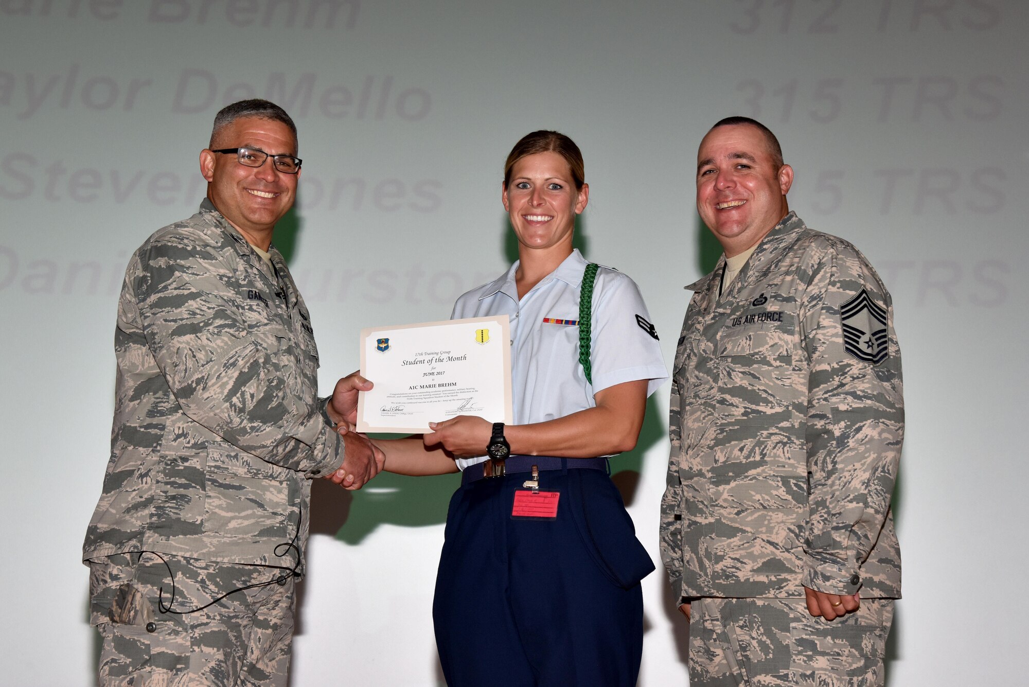 U.S. Air Force Col. Alex Ganster, 17th Training Group commander, presents the 312th Training Squadron Student of the Month award for June 2017 to Airman 1st Class Marie Brehm, 312th TRS student, in the base theater on Goodfellow Air Force Base, Texas, July 7, 2017. (U.S. Air Force photo by Staff Sgt. Joshua Edwards/Released)