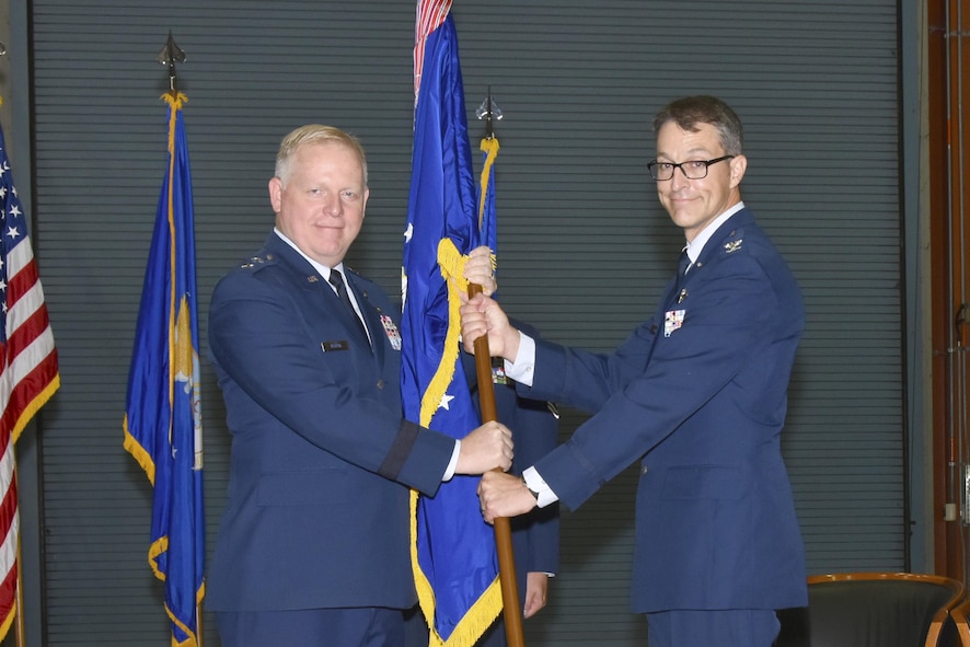 Air Force Test Center Commander Maj. Gen. David A. Harris, left, presents the Arnold Engineering Development Complex flag to the newly-designated commander, Col. Scott A. Cain, during a change of command ceremony July 14 inside the AEDC Large Rocket Motor Test Facility, J-6, located at Arnold Air Force Base, Tennessee. (U.S. Air Force photo/Rick Goodfriend)