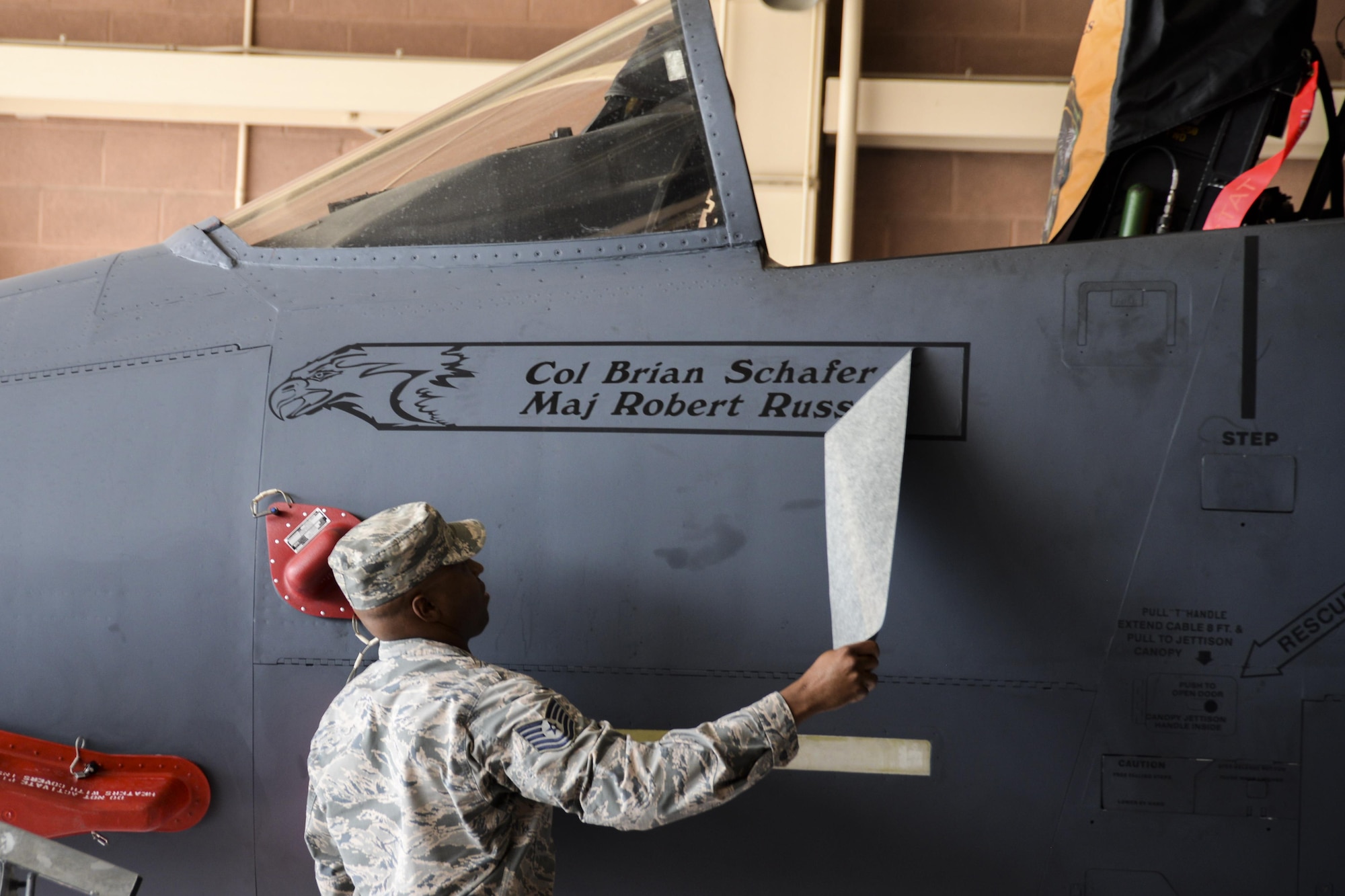 An Airman assigned to the 53rd Test and Evaluation Group reveals the name of the incoming 53rd TEG commander, Col. Brian Schafer, stenciled on the side of the group’s flagship, an F-15 Eagle, at Nellis Air Force Base, Nev., July 11, 2017. It is customary for the flagship of flying squadrons, groups or wings to bear its commander’s name. (U.S. Air Force photo by Airman 1st Class Andrew D. Sarver/Released)
