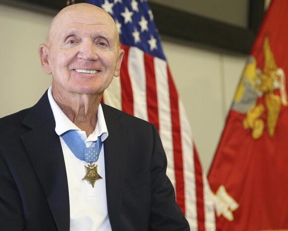 U.S. Marine Corps Medal of Honor recipient Col. Robert J. Modrzejewski ret. poses infront of the American and Marine Corps flag at a room dedication ceremony at the Advanced Infantry Training Battalion, School of Infantry West, Camp Pendleton, Calif;, July 14, 2017. 

The ceremony was held to dedicate a classroom, now called the Hall of Heroes, to the Medal of Honor recipients of the past and present. Colonel Robert J. Modrzejewski, a Medal of Honor recipient who retired from the Marine Corps in 1986, was the ceremony’s guest of honor. (U.S. Marine Corps photo by Pfc. Noah Rudash)