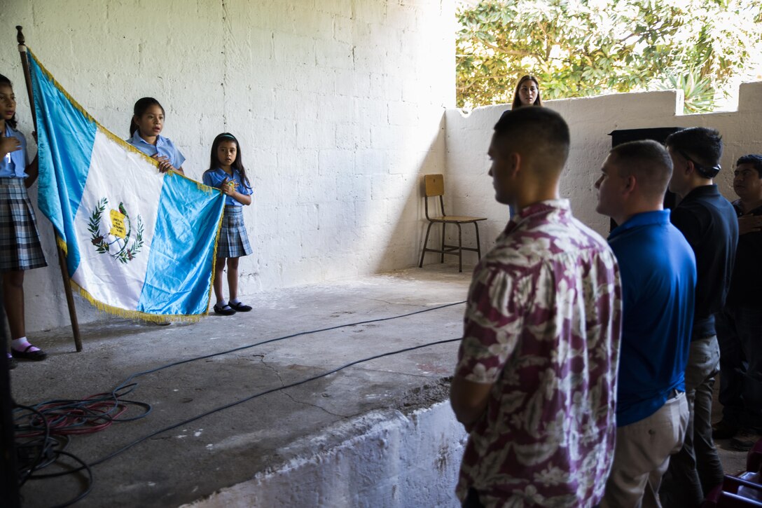 U.S. Marines and sailors with the Logistics Combat Element, Special Purpose Marine Air-Ground Task Force - Southern Command, stand to honor the flag of Guatemala during an opening ceremony for the Official School for Rural Community Housing in Guazacapán, Guatemala, July 7, 2017. The service members volunteered to paint the school and were invited to an opening ceremony to celebrate the renovations with students and their families. The Marines and sailors of SPMAGTF-SC are deployed to Central America to conduct security cooperation training and engineering projects with their counterparts in Belize, El Salvador, Guatemala, and Honduras. (U.S. Marine Corps photo by Cpl. Melissa Martens)