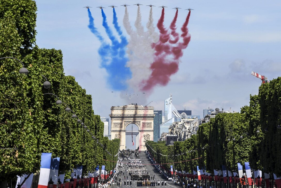 U.S. service members march in the Bastille Day parade in Paris, July 14, 2017, as smoke trails billow overhead from a flyover conducted by French Alpha jets. U.S. troops led the parade in a historic first, to commemorate the centennial of America’s entry into World War I and its long-standing partnership with France. Navy photo by Chief Petty Officer Michael McNabb