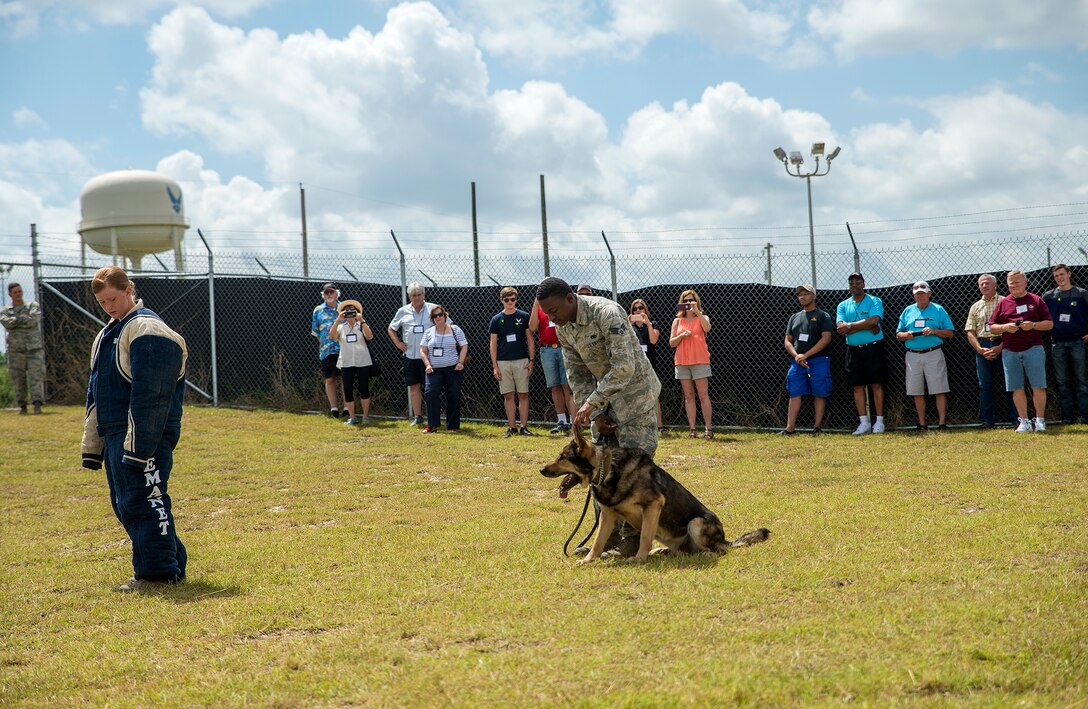 Senior Airmen Sarah Banks and Travis Waddy, 802nd Security Forces Squadron K-9 handler, perform a controlled agression demonstration for members of the National Corvette Restorers Society July 13, 2017 at Joint Base San Antonio-Lackland, Texas. The visit also included tours of a C-5M Super Galaxy aircraft and United States Air Force Airman Heritage Museum and Enlisted Character Development Center. (U.S. Air Force photo by Benjamin Faske)