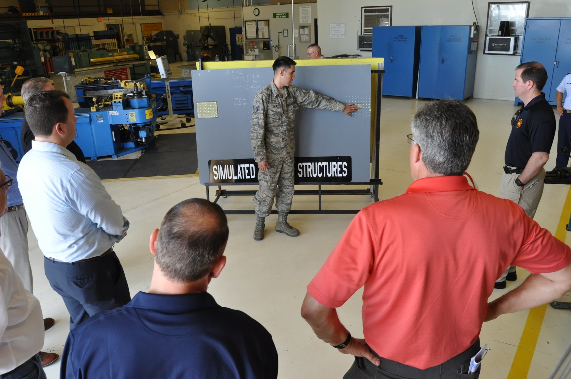 Staff Sgt. Ivan Vela, 433rd Maintenance Squadron aircraft structural technician, explains the processes his unit uses to make repairs to the C-5M Super Galaxy to honorary commanders visiting the 433rd Maintenance Group during a tour July 15, 2017.  During the tour, the 433rd Airlift Wing honorary commanders witnessed the Assumption of Command ceremony for the 433rd MXG, visited a C-5M Super Galaxy on the flight line, the metals technology and sheet metal shops, the propulsion shop and visited with members of the Maintenance Operations Center.  (U.S. Air Force photo/Senior Airman Bryan Swink)