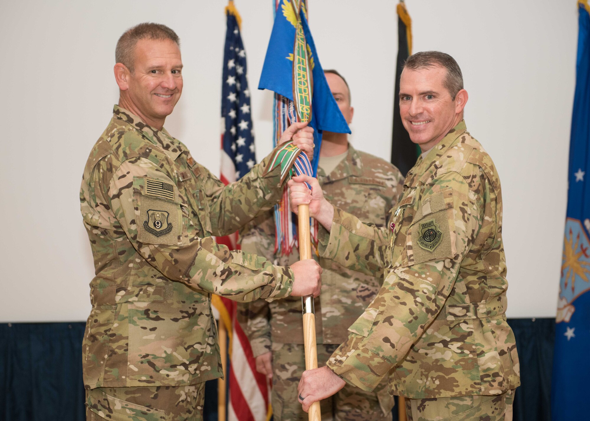 Col. Charles D. Bolton (right), the 386th Air Expeditionary Wing outgoing commander passes the 386th AEW guidon to Maj. Gen. Dirk D. Smith, the deputy commander, Combined Joint Task Force-Operation Inherent Resolve, U.S. Central Command and the commander, 9th Air Expeditionary Task Force-Levant, U.S. Air Forces Central Command signifying his relinquish of command during a change of command ceremony at an undisclosed location in Southwest Asia, July 12, 2017. Bolton will move on to his next assignment as the deputy director of intelligence, operations and nuclear integration for flying at Headquarters Air Education and Training Command, Joint Base San Antonio Randolph, Texas. (U.S. Air Force photo by Tech. Sgt. Jonathan Hehnly)