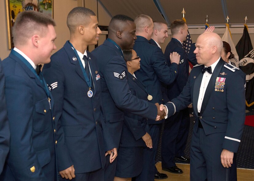 Col. Roman L. Hund, installation commander, congratulates Senior Airman Shemrom R. Ross on completing Airman Leadership School following a graduation ceremony at the Minuteman Commons July 14. By completing the course, the 12 graduates are now able to supervise junior members in their respective organizations. (U.S. Air Force photo by Rick Berry)