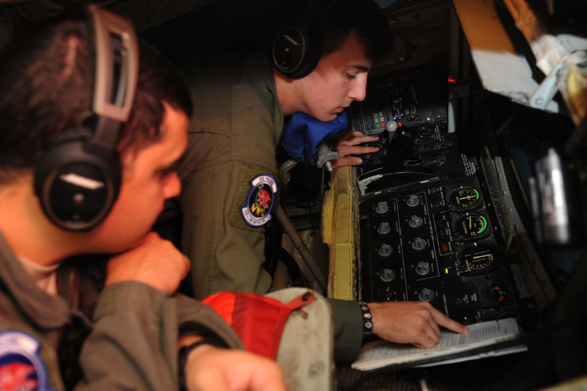 Staff Sgt. Lane Nunier, left, 350th Air Refueling Squadron boom operator instructor, observes Airman 1st Class Patrick Napolitano, 350th ARS boom operator, as he completes a checklist prior to a refueling mission, July 12, 2017, over the Pacific ocean. As an instructor, Nunier observes and asks questions to new boom operators to gauge their level of understanding to ensure every new boom is qualified before they are able to operate on their own. (U.S. Air Force photo/Staff Sgt. Rachel Waller)