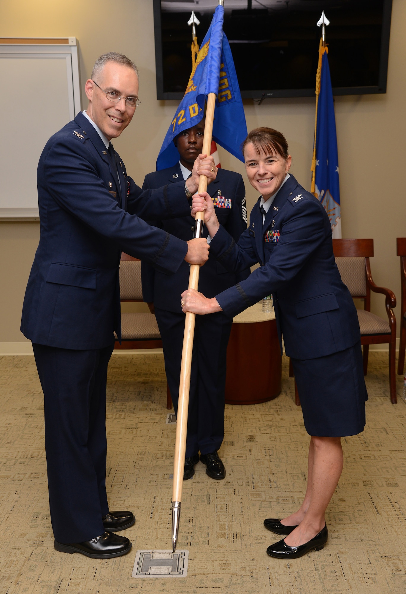 72nd Medical Group Commander Col. Christopher Grussendorf passes the 72nd Dental Squadron guidon to Col. Dawn Wagner during a change of command ceremony July 10 in Heritage Hall of the Tinker Clinic. Col. Michael Suhler was the outgoing squadron commander and 72nd MDG deputy commander and Senior Master Sgt. Mary Lake served as guidon bearer during the formal ceremony. Col. Wagner will oversee 54 assigned personnel responsible for treating 8,000 active duty personnel. (Air Force photo by Kelly White)