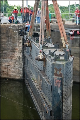 Workers drilled two holes through the top of the gate then installed pins through the holes. Each pin was nine inches in diameter and four feet six inches long. Once the pins were in place, collars were welded around the pins to help stabilize them. The final step was to install pad eyes so a crane could lift each gate and gently lay it down on a waiting platform barge.