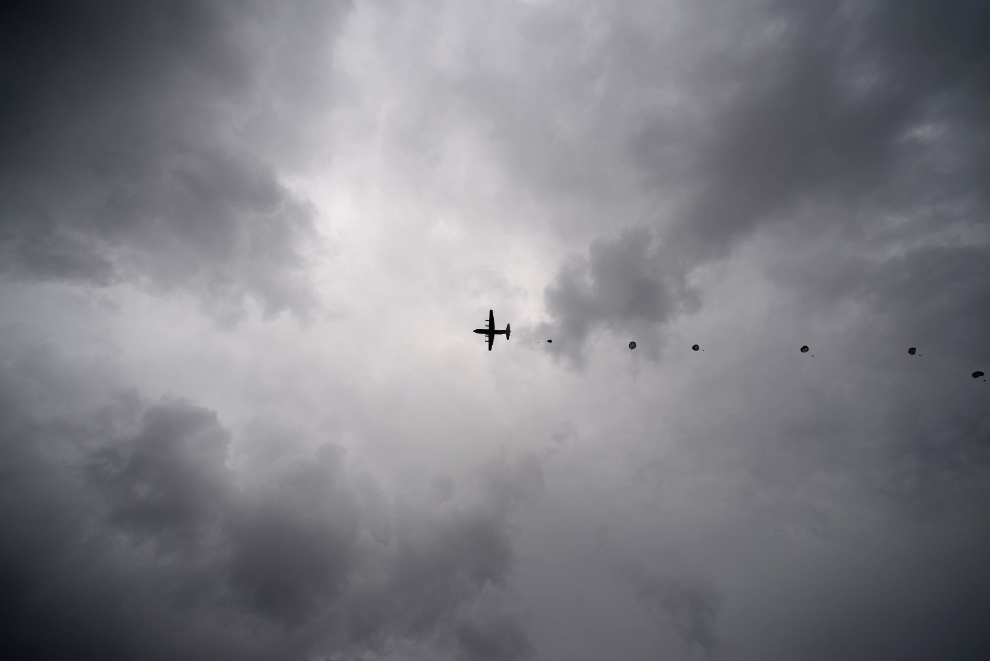 Parachutists jump out of the back of a C-130J Super Hercules assigned to the 37th Airlift Squadron at International Jump Week in Bitburg, Germany, July 11, 2017. International Jump Week allows partner nations to standardize ways of dropping paratroopers and organizers boosted relations between the 13 nations involved. (U.S. Air Force photo by Airman 1st Class D. Blake Browning)