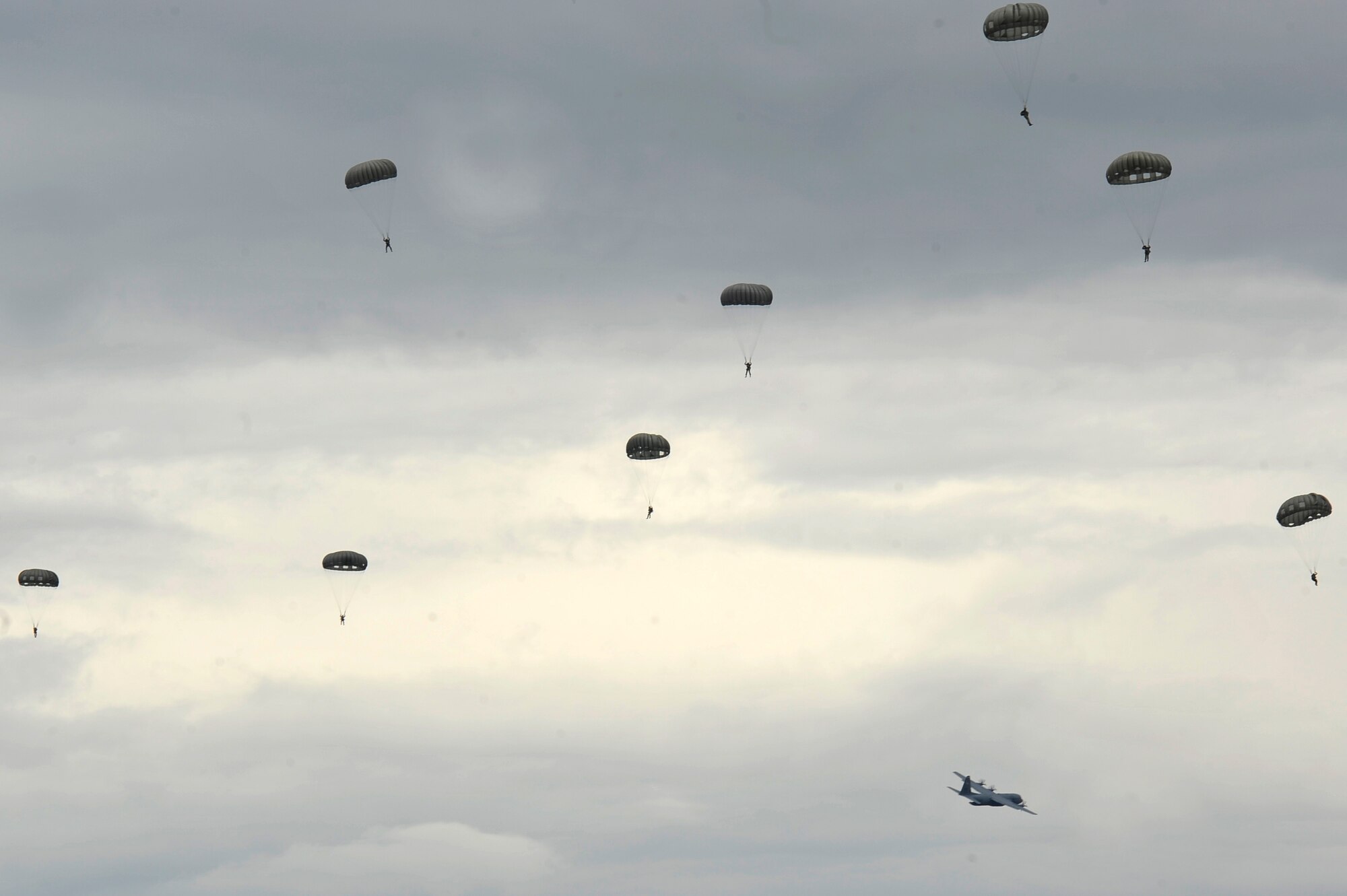 Parachutists descend as a C-130J Super Hercules assigned to the 37th Airlift Squadron flies away during International Jump Week in Bitburg, Germany, July 11, 2017. The training performed during this exercise standardizes parachuting between 13 partner nations. (U.S. Air Force photo by Airman 1st Class D. Blake Browning)