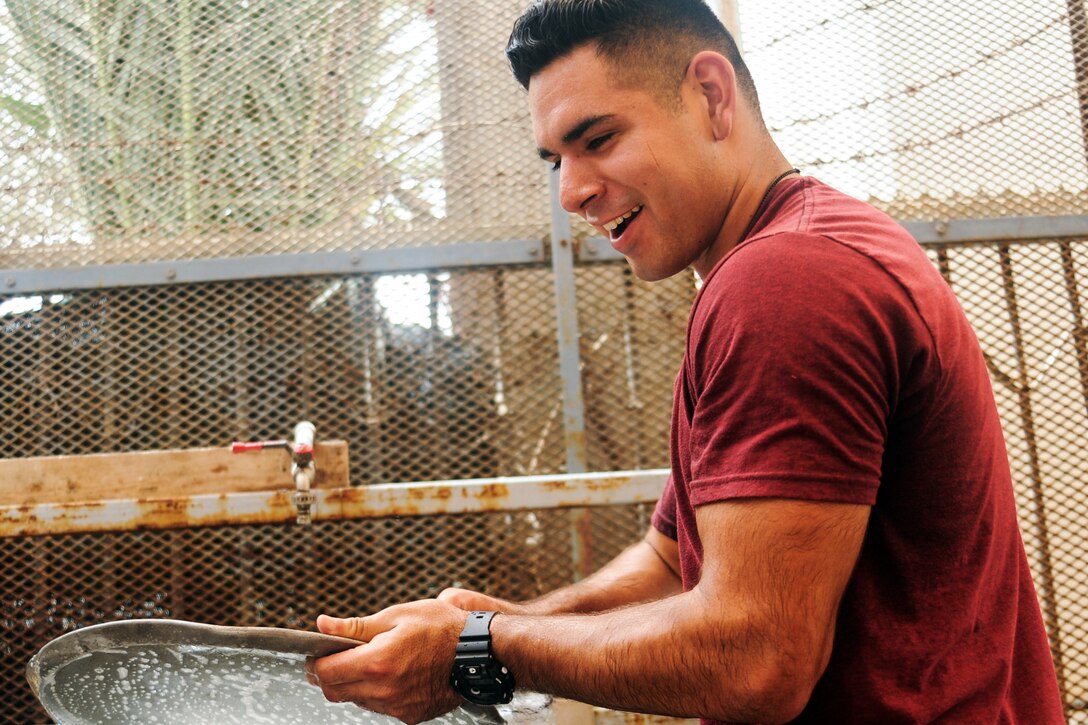 Army Spc. Jesus Gomez washes the pans used to cook lunch at the Caritas refugee compound in Djibouti, July 6, 2017. Gomez is a battalion medic assigned to 1st Battalion, 153rd Infantry Regiment, 39th Infantry Brigade Combat Team. Army National Guard photo by Spc. Victoria Eckert
 