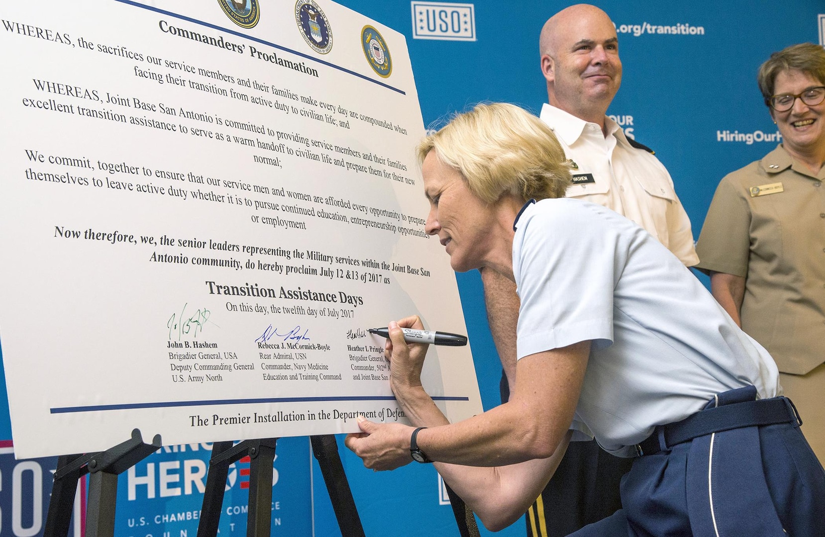 Brig. Gen. Heather Pringle (left), commander of the 502nd Air Base Wing and Joint Base San Antonio, signs the Commanders' Proclamation July 12 during the Transition Assistance Days at the Fort Sam Houston Community Center as Brig. Gen. John Hashem, deputy commanding general, U.S. Army North; and Rear Adm. Rebecca McCormick-Boyle, commander, Navy Medicine Education and Training Command, look on.